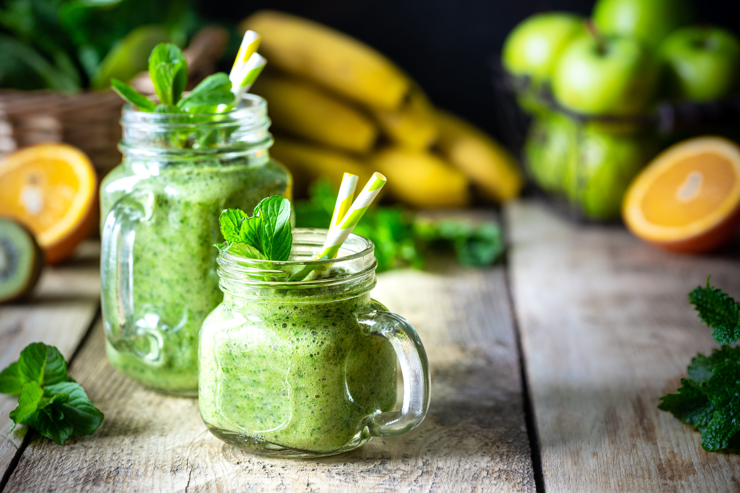 Two healthy green smoothies with spinach, banana, apple, kiwi and mint in glass jar and ingredients. Detox, diet, healthy, vegetarian food concept
